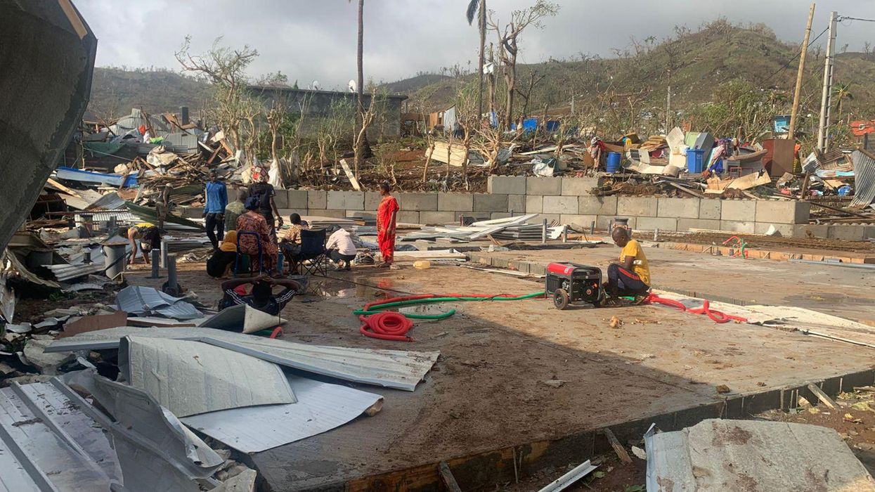 residents sitting among piles of debris of metal sheets and wood after homes were destroyed by the cyclone Chido