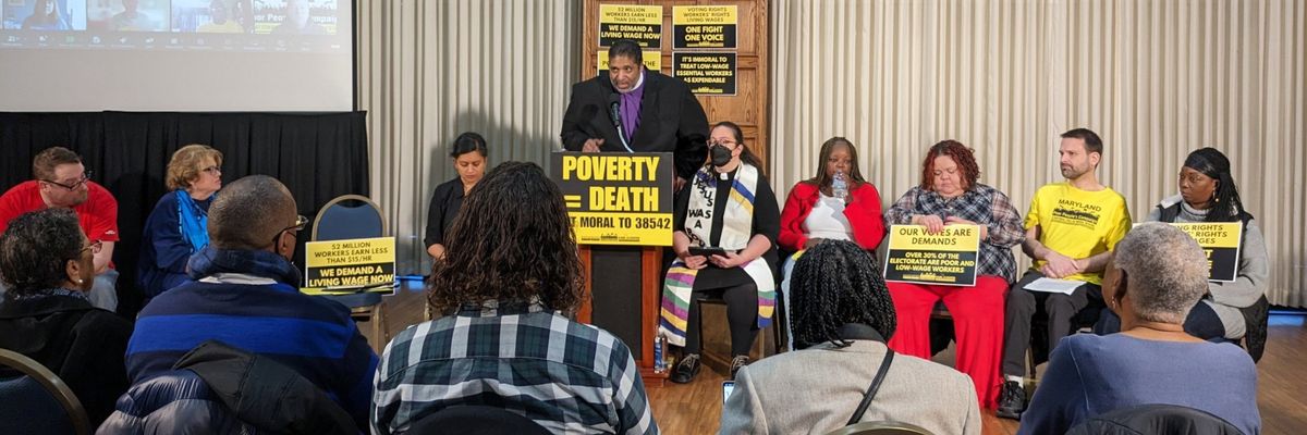 Rev. Dr. William Barber speaks at a podium with a sign reading "Poverty = Death." 