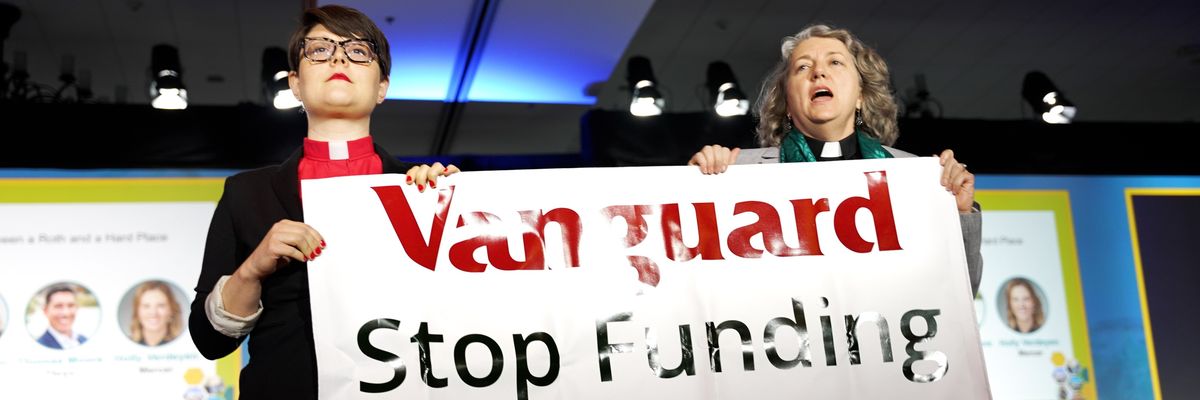 Revs. Amy Brooks and Chelsea McMillan stand with a sign reading, "Vanguard: Stop funding fossil fuels."
