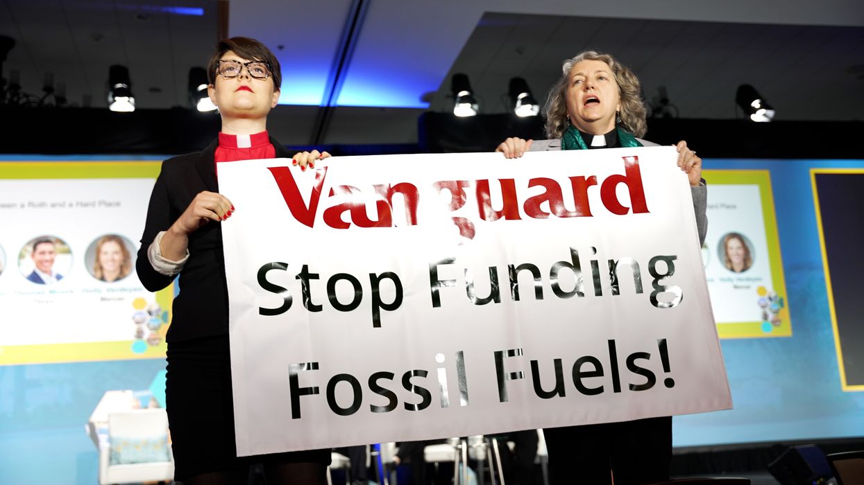 Revs. Amy Brooks and Chelsea McMillan stand with a sign reading, "Vanguard: Stop funding fossil fuels."