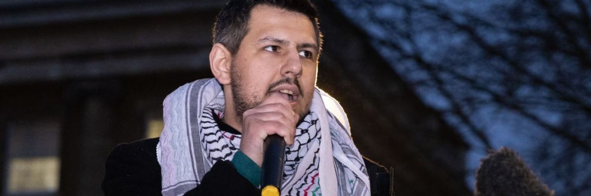 Richard Medhurst speaks wearing a keffiyeh