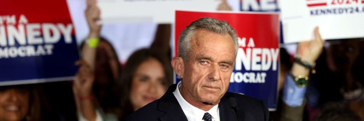Robert F. Kennedy Jr. stands in front of campaign signs.