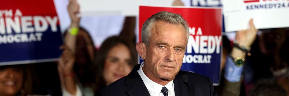 Robert F. Kennedy Jr. stands in front of campaign signs.