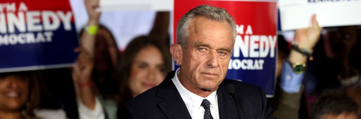 Robert F. Kennedy Jr. stands in front of campaign signs.