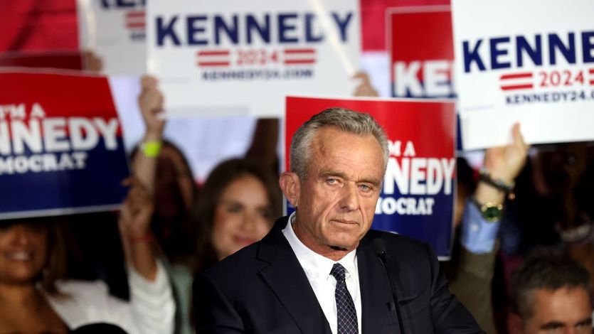Robert F. Kennedy Jr. stands in front of campaign signs.