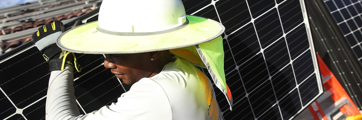 Roger Garbey, from the Goldin Solar company, installs a solar panel system on the roof of a home on January 23, 2018 in Palmetto Bay, Florida.