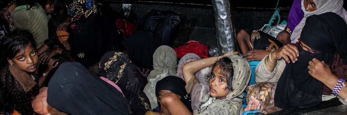 Rohingya refugees sit on a wooden boat