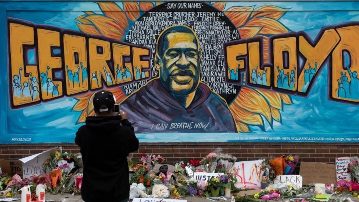Ronald Scott, a central neighborhood resident for more than 10 years, takes a photo of the memorial mural over flowers and banners laid in the memory of George Floyd outside of Cup Foods on May 29, 2020.