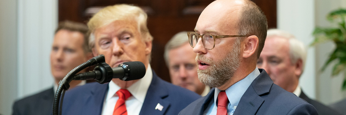 Russ Vought speaks while Donald Trump looks on