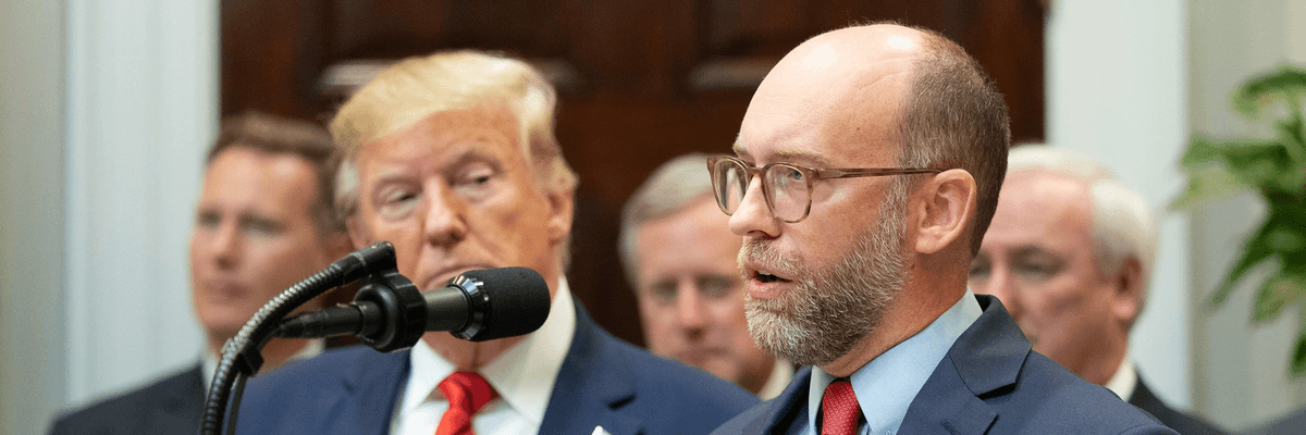 Russ Vought speaks while Donald Trump looks on
