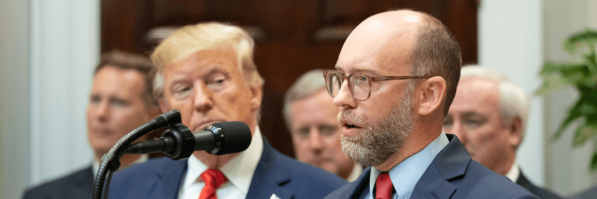 Russ Vought speaks while Donald Trump looks on