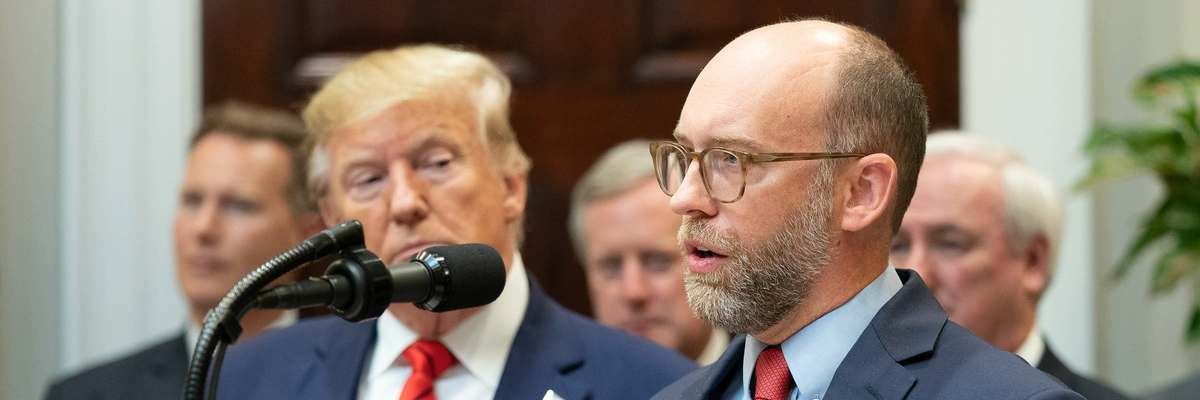 Russ Vought speaks while Donald Trump looks on
