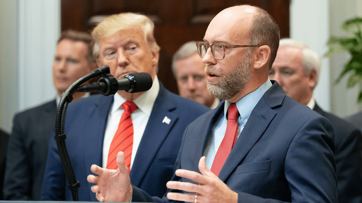 Russ Vought speaks while Donald Trump looks on