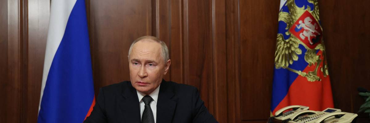 Russia's President Vladimir Putin sits at a table.