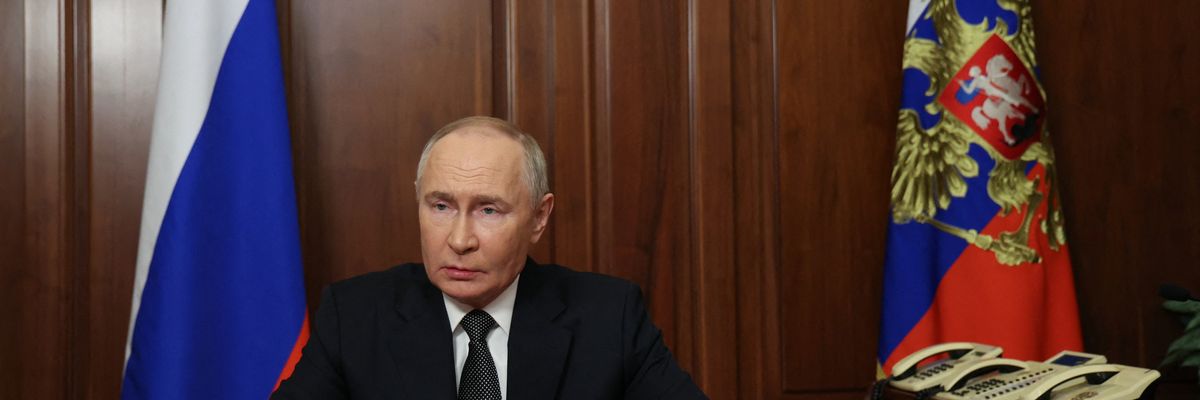 Russia's President Vladimir Putin sits at a table.