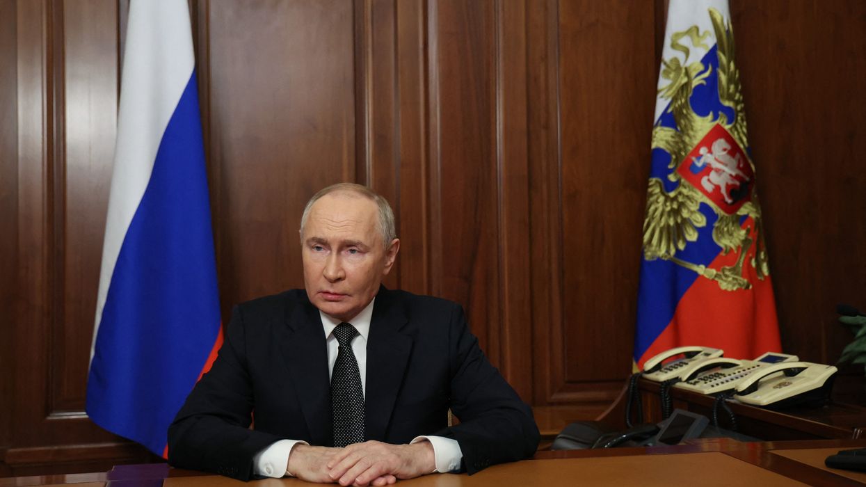 Russia's President Vladimir Putin sits at a table.