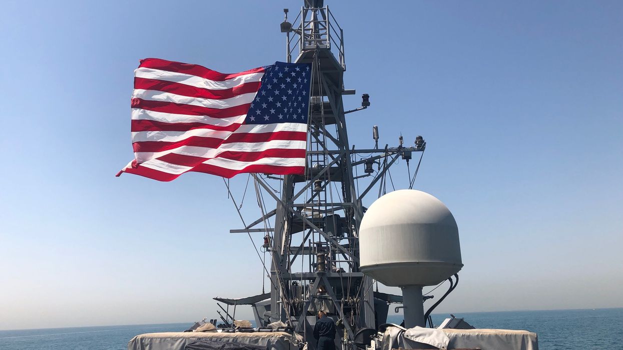 Sailors on board the USS Whirlwind display a U.S. flag