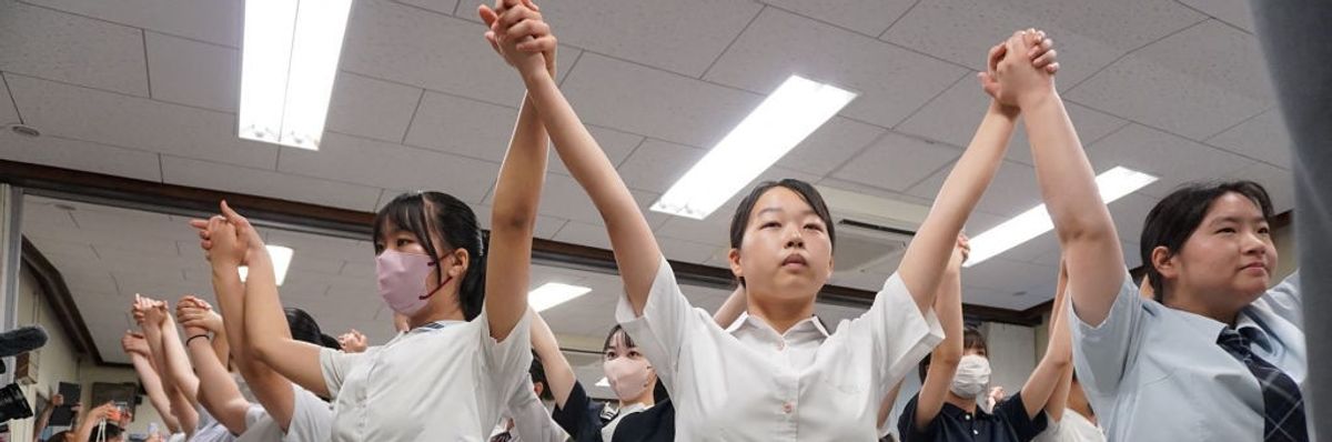 School children pray for peace with lifted, linked hands.