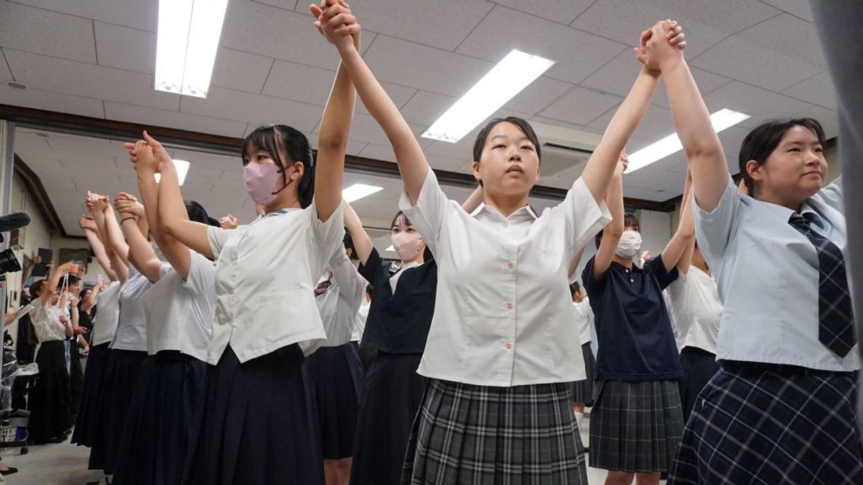School children pray for peace with lifted, linked hands.