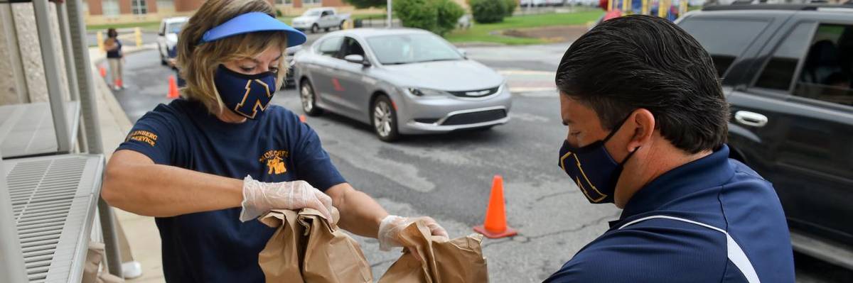School staff distribute free school lunches.