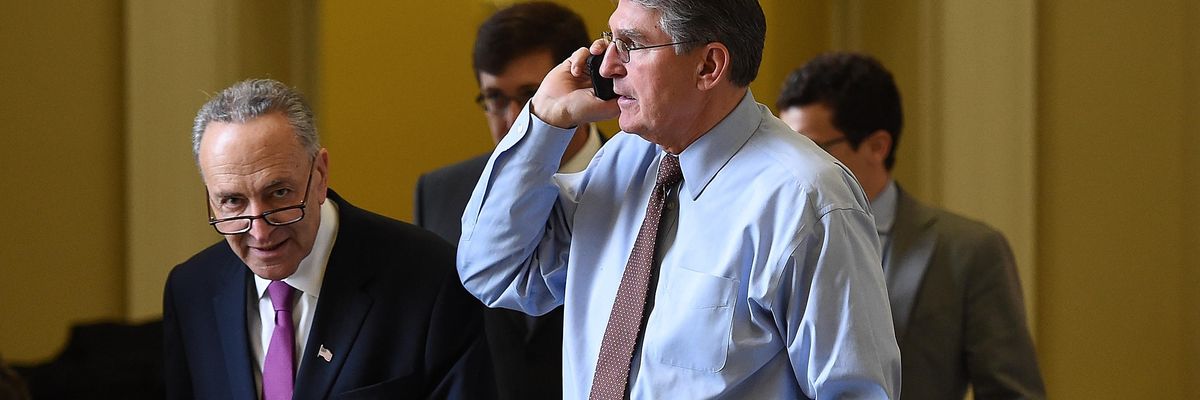 Schumer passes Manchin as he speaks on the phone