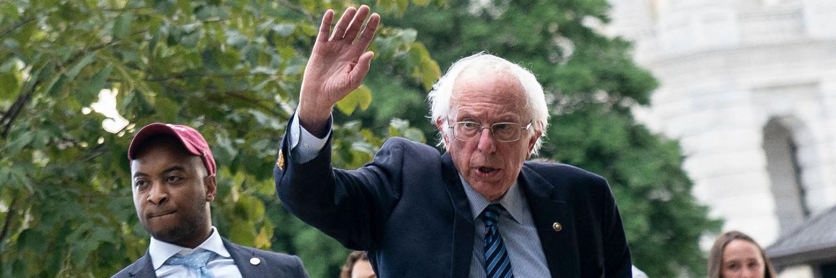Sen. Bernie Sanders waves at demonstrators on Capitol Hill