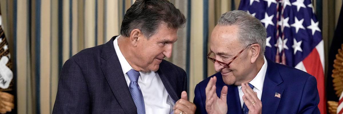 Sen. Joe Manchin and Senate Majority Leader Chuck Schumer clap during a White House event