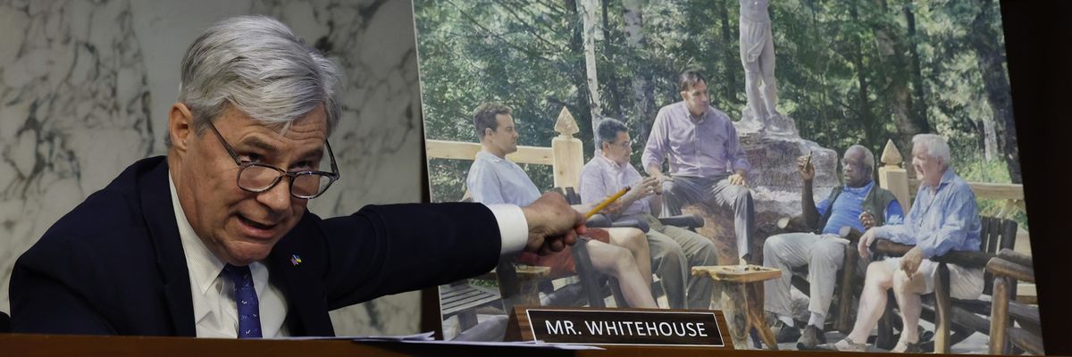 ​Sen. Sheldon Whitehouse (D-R.I.) displays a copy of a painting featuring Harlan Crow (right), Supreme Court Justice Clarence Thomas (second from right), and other right-wing figures during a Senate Judiciary Committee hearing on May 2, 2023.
