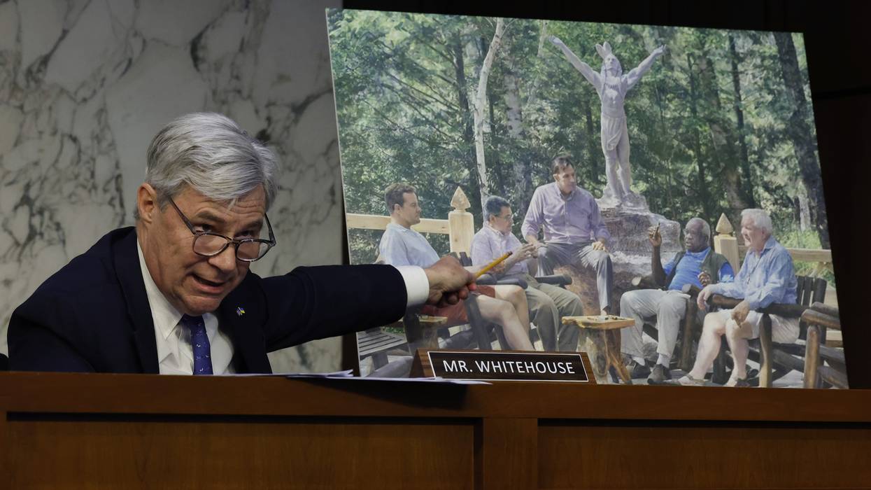 Sen. Sheldon Whitehouse (D-R.I.) displays a copy of a painting featuring Harlan Crow (right), Supreme Court Justice Clarence Thomas (second from right), and other right-wing figures during a Senate Judiciary Committee hearing on May 2, 2023.