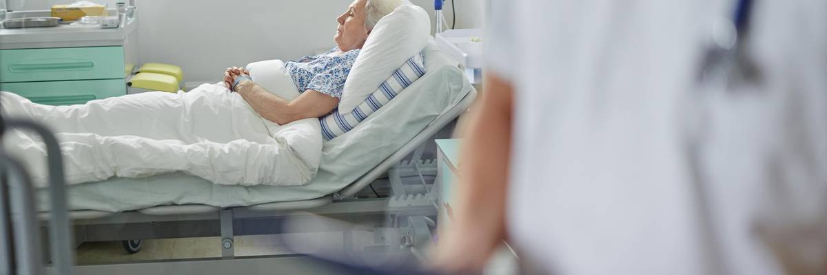 senior woman lies in bed receiving care.