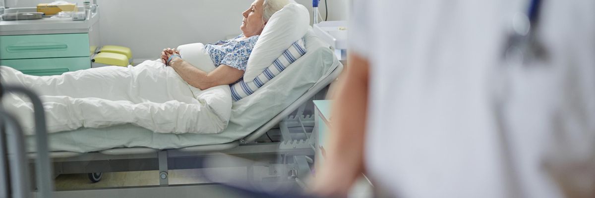 senior woman lies in bed receiving care.