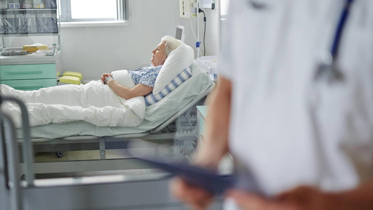 senior woman lies in bed receiving care.