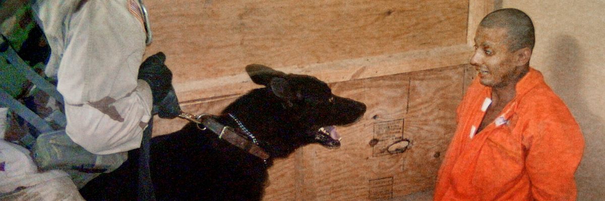 Sgt. Michael Smith uses a dog to torture a terrified Abu Ghraib prisoner in an orange jumpsuit.