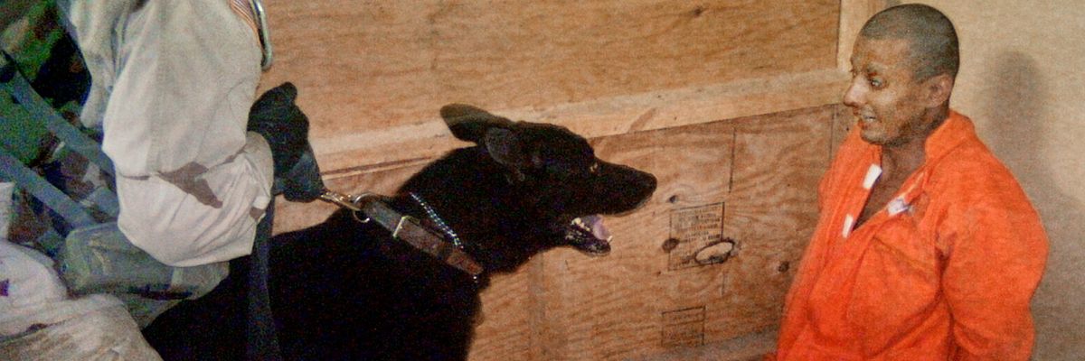 Sgt. Michael Smith uses a dog to torture a terrified Abu Ghraib prisoner in an orange jumpsuit.