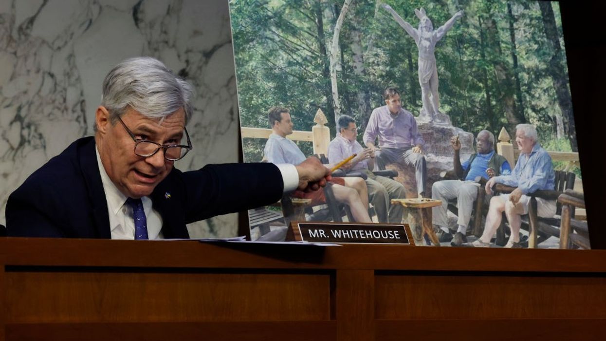 Sheldon Whitehouse points to photo of Clarence Thomas and Harlan Crowe and Leonard Leo