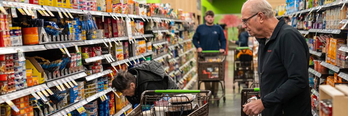 Shoppers look at a canned fish display
