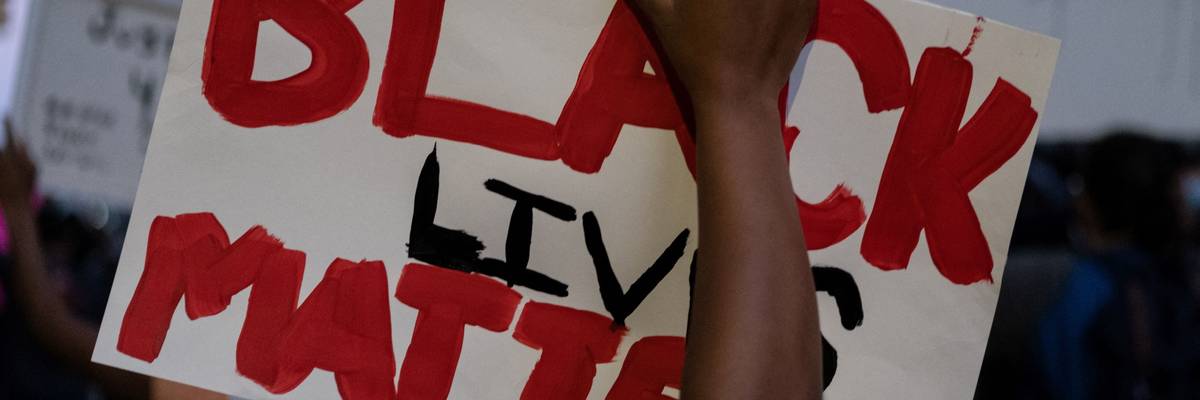 Sign held aloft during a 2020 Detroit protest after the death of George Floyd.