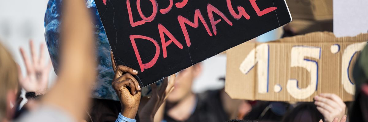 Sign reads "Pay Up for Loss and Damage"