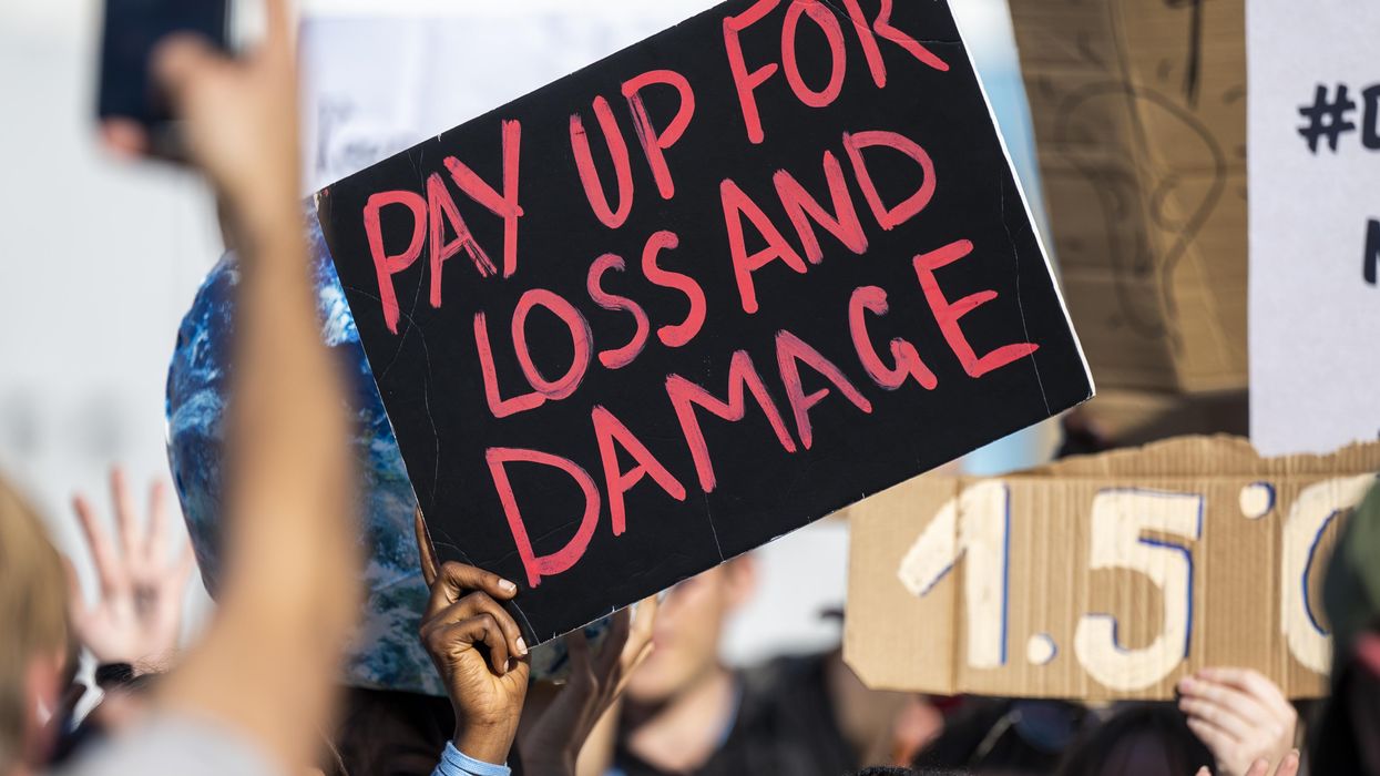 Sign reads "Pay Up for Loss and Damage"
