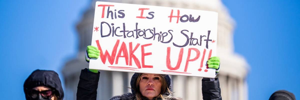 Sign says: "This is how dictatorships start—WAKE UP!"
