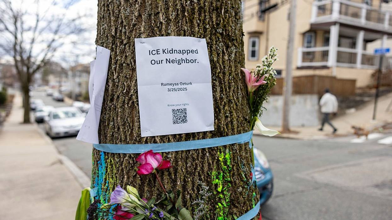 Signage and flowers are placed on a tree next to where ICE agents apprehended Rumeysa Ozturk
