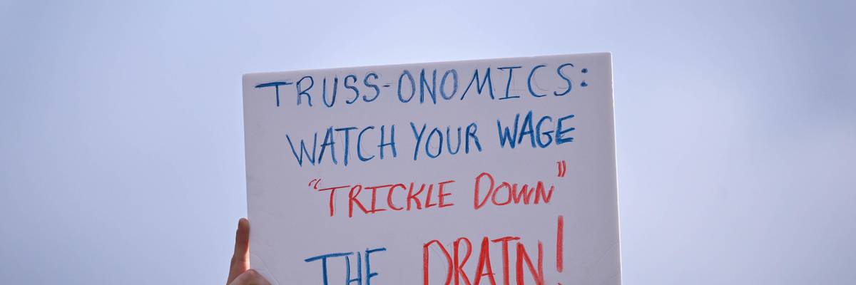 Signs reads "Truss-onomics: Watch your wage 'trickle down' the drain!"