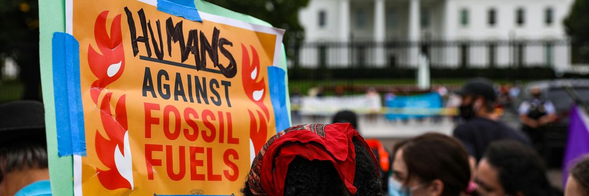 Signs says "Humans agsinst fossil fuels"