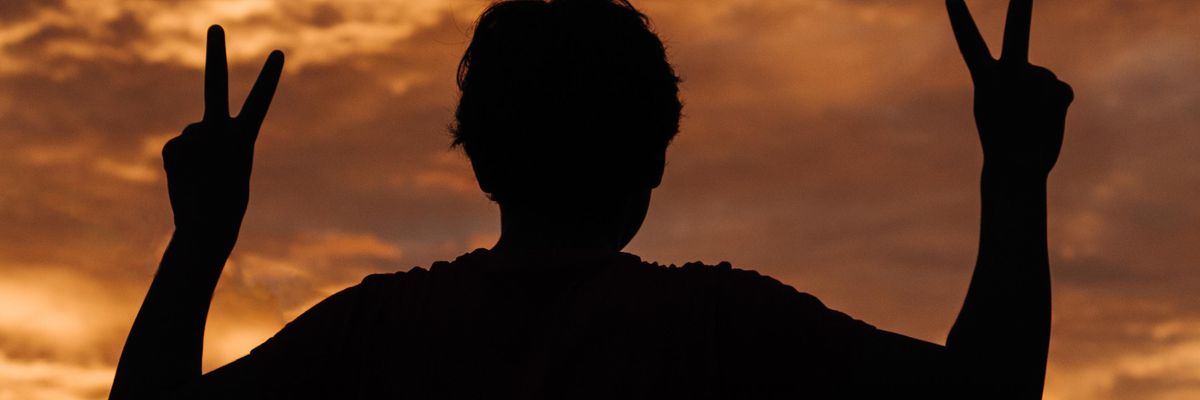 silhouette of person making V for victory symbol