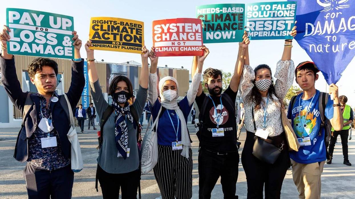 Six protestors hold signs demanding loss and damage reparations.