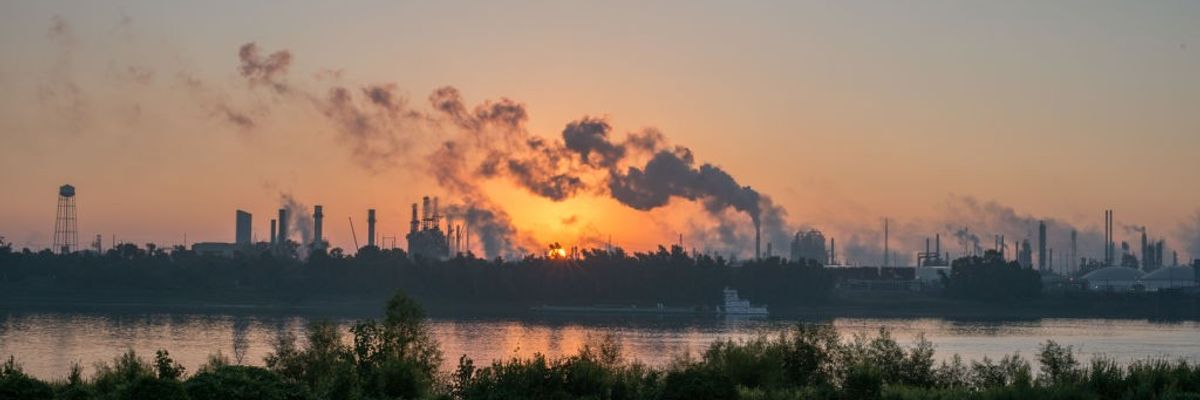 smoke billowing from factories behind river