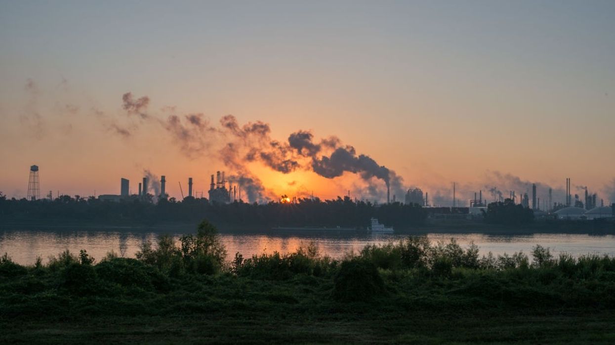 smoke billowing from factories behind river