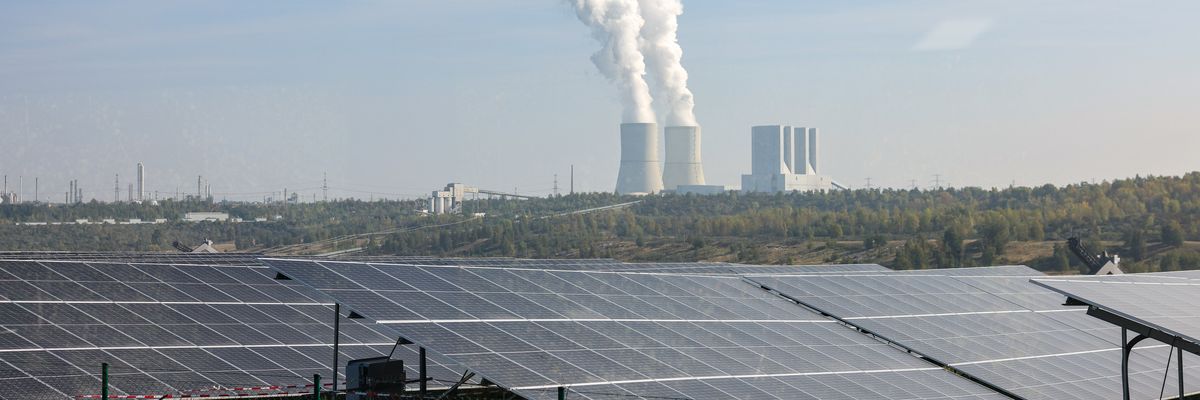 Solar panels in front of a smoke stack.