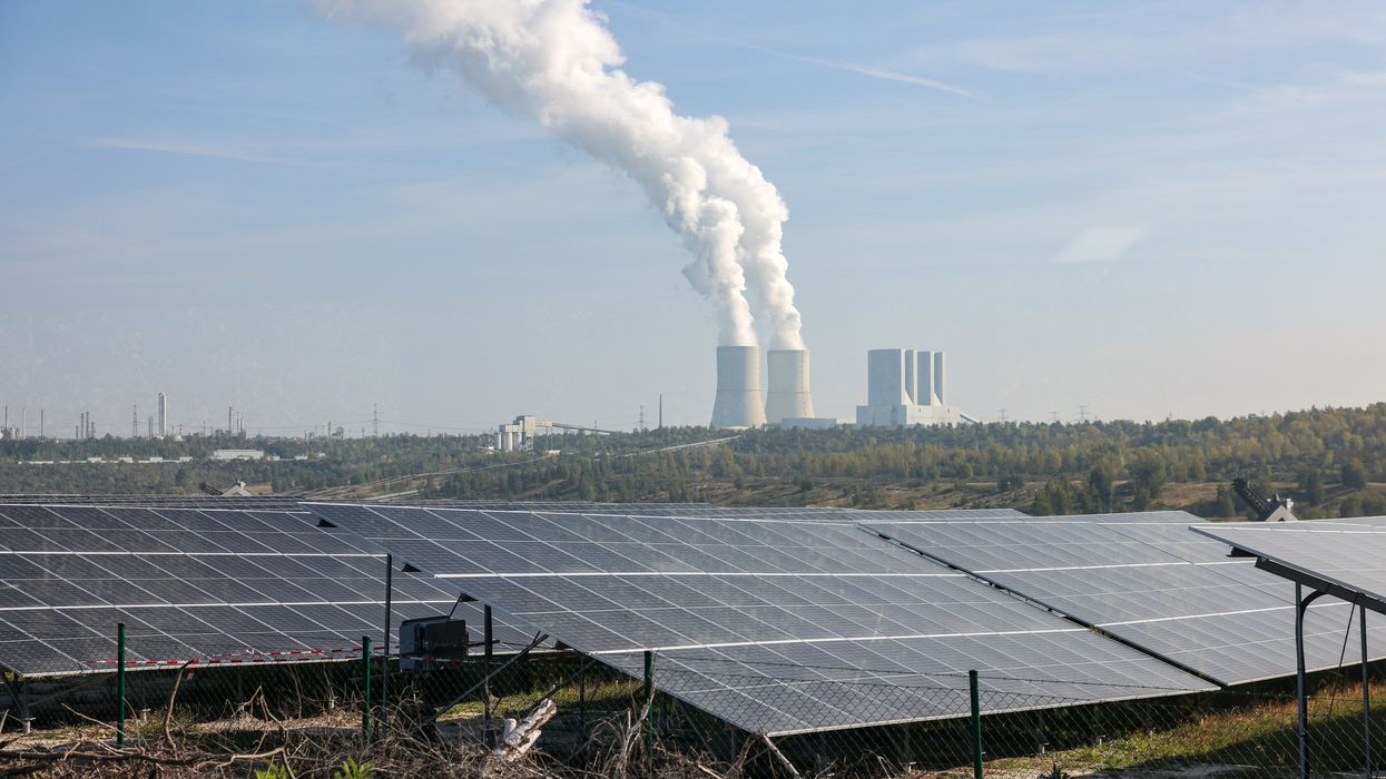 Solar panels in front of a smoke stack.