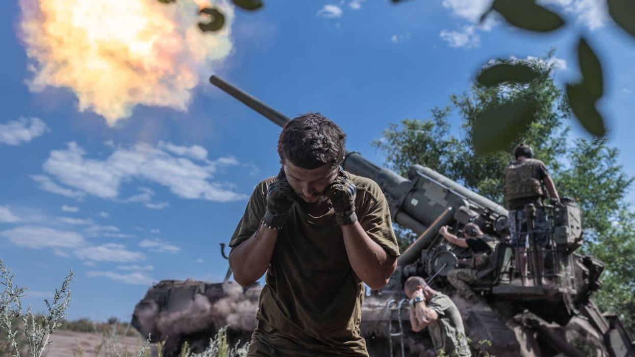 Soldier covers ears during artillery fire in Ukraine